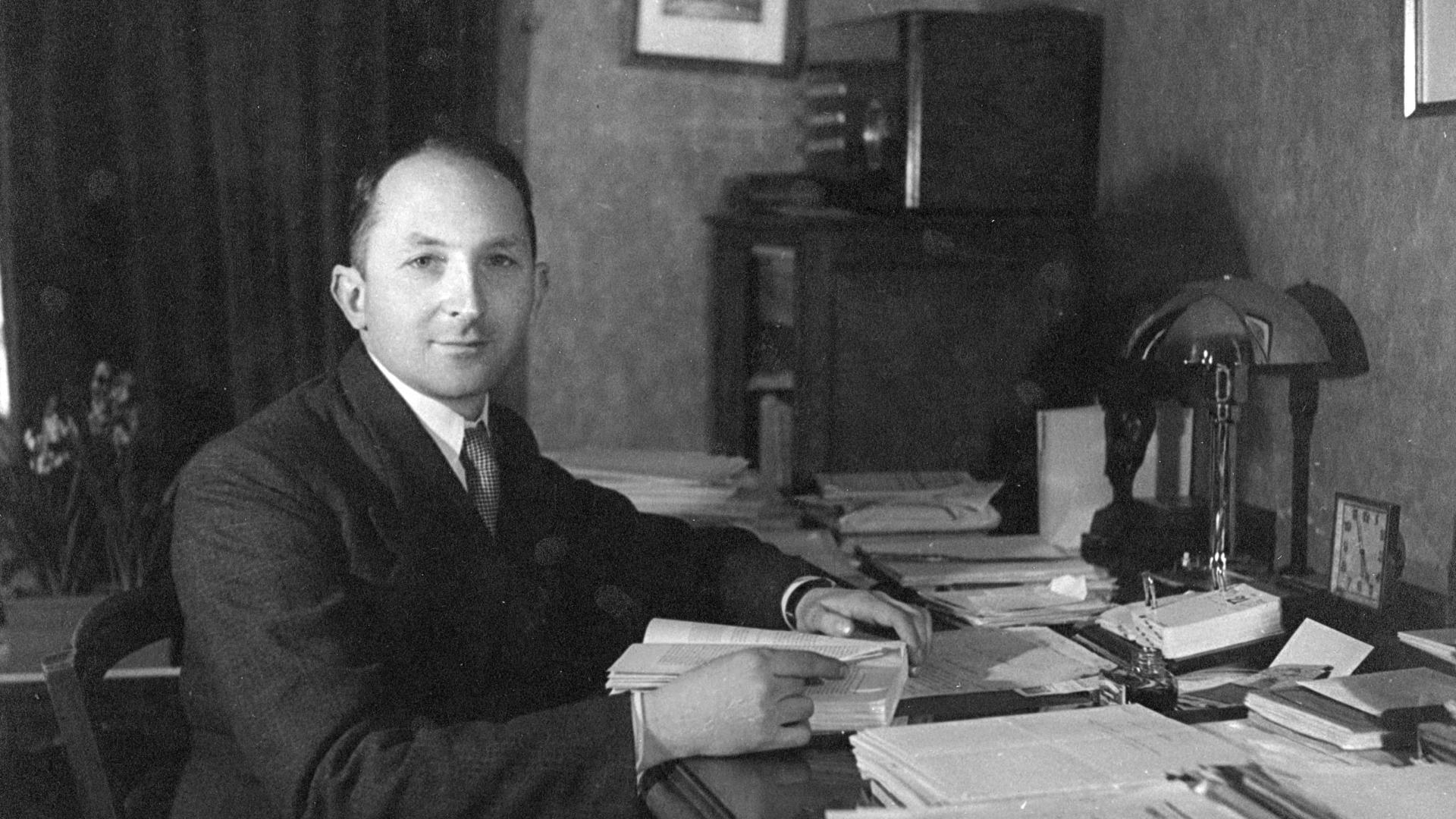 Photo en noir & blanc montrant Jean Claparède, un homme d'une quarantaine d'années, assis à son bureau.