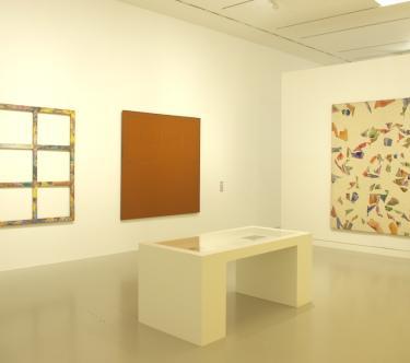 Vue d'une salle du musée avec un banc et plusieurs œuvres abstraites contemporaines.