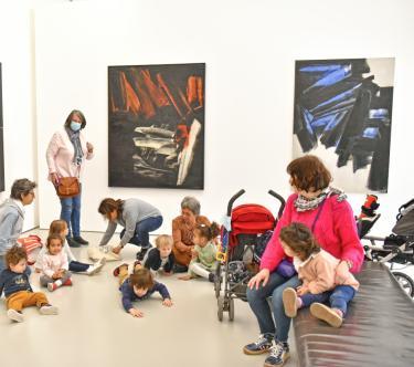 Dans une salles Soulages du musée, on voit un groupe d'assistantes maternelles avec des bébés et des poussettes.