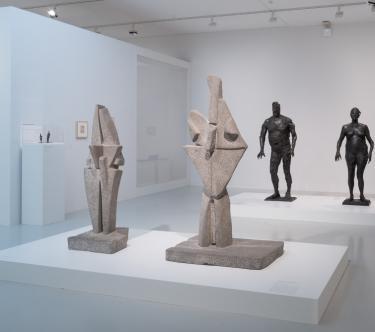 Dans une salle de l'exposition Germaine Richier, on voit quatre œuvres de la sculptrices : deux sculptures géométriques en pierre représentant des formes vaguemetn humanoïdes et deux sculptures en bronze représentant un homme et une femme stylisés.