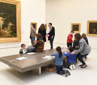 Plusieurs familles regardent des tableaux dans une salle du musée.