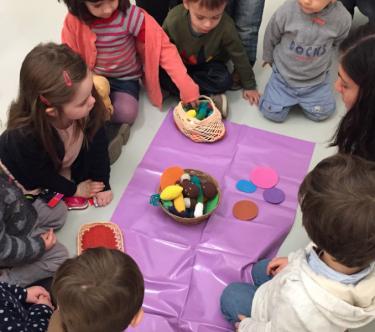 Un groupe d'enfants assis autour d'un tapis de jeu.