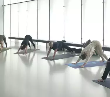 Dans la salle Soulages, plusieurs personnes sont alignées sur des tapis de gymnastique et font des exercices de Pilates.